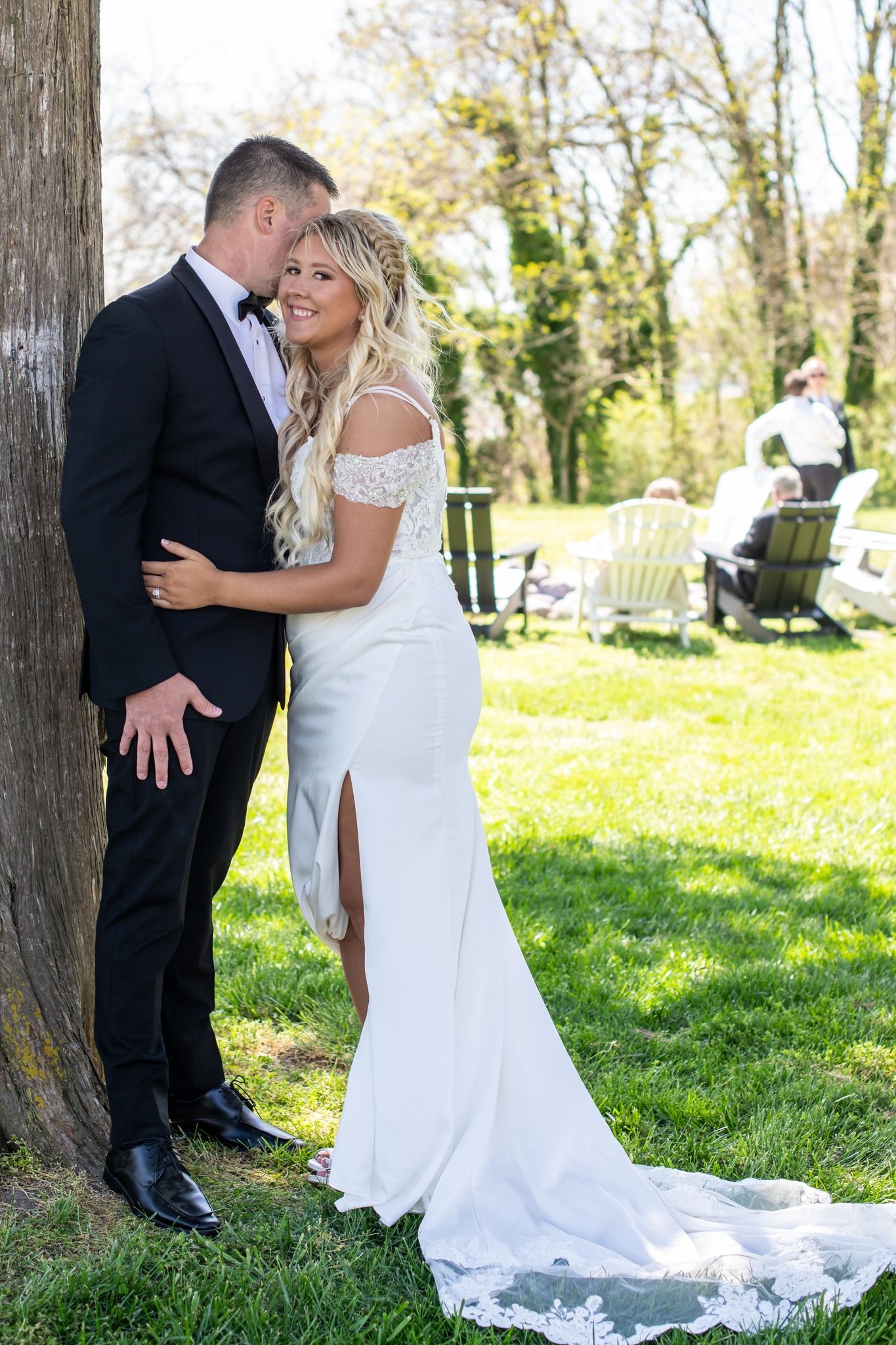 Bride and groom sharing a quiet moment beneath a leafy tree after their wedding ceremony.